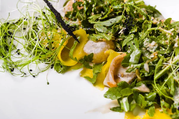 Kalamarlı salata, taze filizler, roka, hindiba, biber, dantel cips, salata ve susam tohumlu hafif bir arka planda.