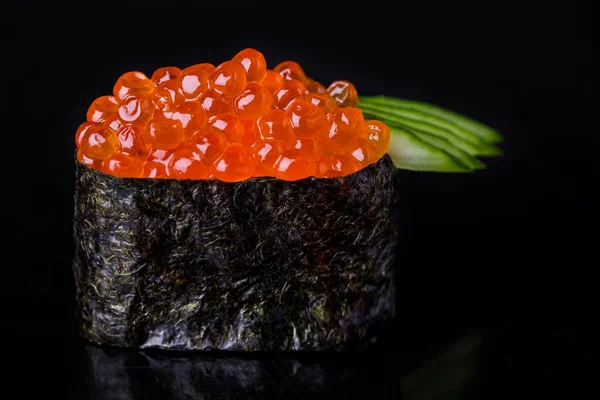 Roll with salmon caviar, cucumber, avocado, rice, nori and Philadelphia cheese on a black mirror background