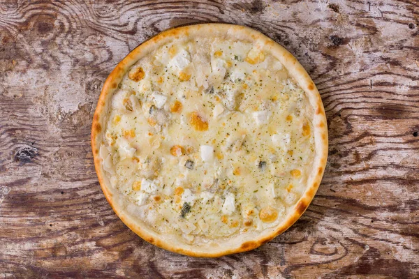 Pizza with different types of cheese on a wooden table