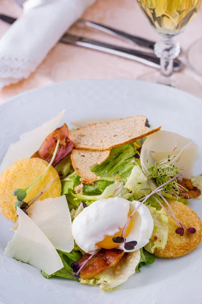 Pastırmalı salata, sahanda yumurta, lahanalar, kızarmış ekmek, salata, peynir tabakta bir bardak şarapla birlikte.