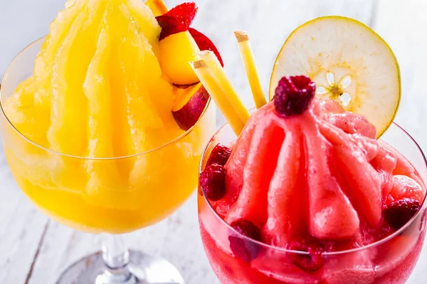 Ice cream with raspberry jam and pear in a glass, and second ice cream with orange jam and apple in a glass on a light background. Horizontal orientation