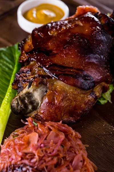 Hardallı, marullu ve haşlanmış lahanalı ahşap bir tahtada domuz budu.