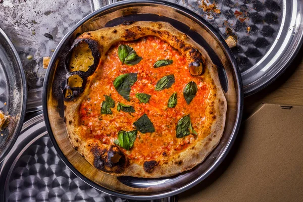 Pizza with cheese and basil in a plate on the table
