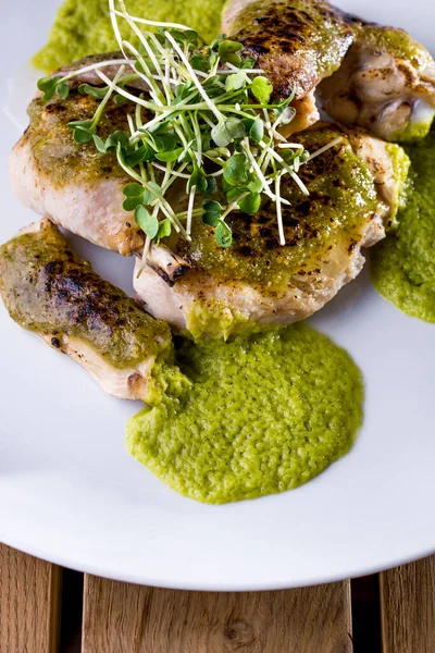 Kemiklerde çiğ tavuk, fasulye salatası ve yeşil soslu beyaz yuvarlak tabak. Dikey yönelim