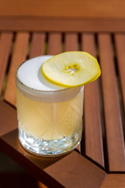 Cocktail with ice, apple and froth in a glass on the table