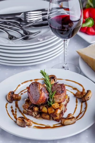 Biberiyeli kızarmış sığır eti dilimleri, biber, çatal bıçaklı bir tabakta mantar ve bir sepet ekmek. Dikey yönelim