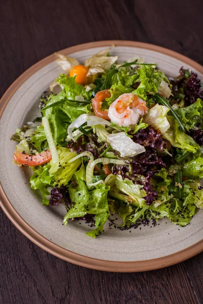 Karidesli salata, turp, marul, salata, susamlı hindiba, roka ve tahtadan bir tabakta susam tohumu.