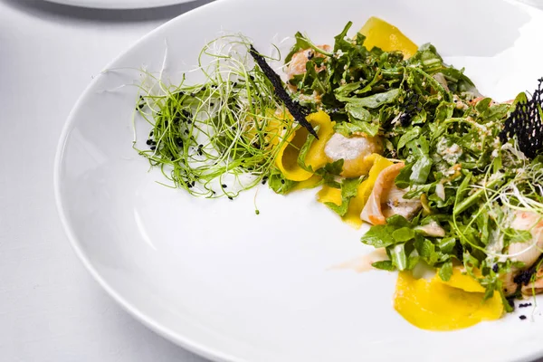 Kalamarlı salata, taze filizler, roka, hindiba, biber, dantel cips, salata ve susam tohumlu hafif bir arka planda.