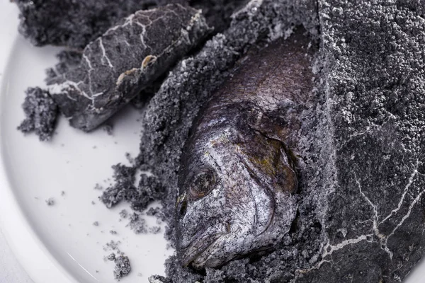 Dorado üzerine gri tuz, limon, kiraz domatesleri ve beyaz bir tabakta salata. Yatay yönelim