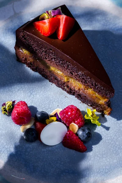 Piece of cake with strawberries, raspberries, blueberries, meringues, jam and chocolate in a plate