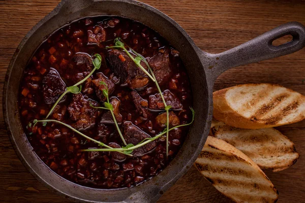 Kızarmış biftek, taze filizlenmiş sos, siyah tabakta salata. Dikey yönelim