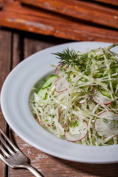 Lahanalı salata, turp, ahşap bir masada çatalla dereotu.