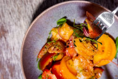 Domatesli salata, bezelye filizi, çiçek yaprakları, ahşap bir tabakta ekmek ve fesleğen.