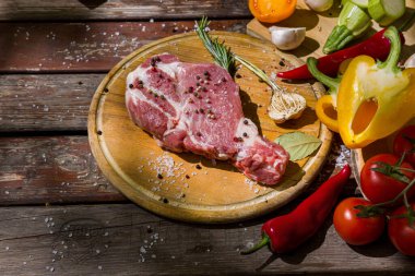 Çiğ et, sarımsak, domates, kırmızı sıcak ve tatlı biber, kabak, defne yaprağı, biberiye, ahşap bir tahta ve ahşap masa üzerinde tuz ve biber. Yatay yönelim