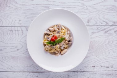 Kalamar, şampiyon, domates, fesleğen ve soslu spagetti beyaz ahşap bir masada.