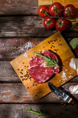 Çiğ domuz eti sarımsaklı, kiraz domatesli, defne yapraklı, mantarlı, kırmızı biberli ve ahşap bir masa üzerinde bıçaklı siyah biberli. Dikey yönelim