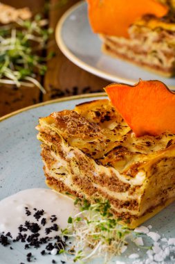 Ekşi kremalı lazanya ve ahşap bir masada lahanalar.