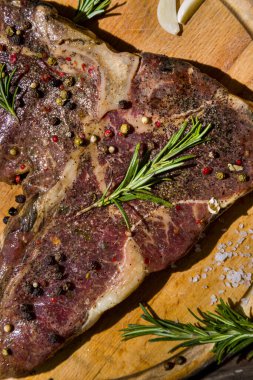 Kemiğin üzerinde ızgara et, ahşap bir tahta ve ahşap masa üzerinde sarımsak, biberiye, tuz ve biber. Dikey yönelim