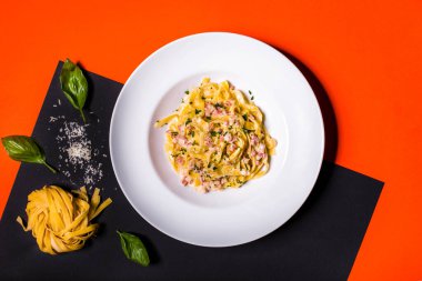 Peynirli makarna, fesleğen, maydanoz ve et sarı-siyah bir arka planda dağınık bakkaliye ile bir tabakta