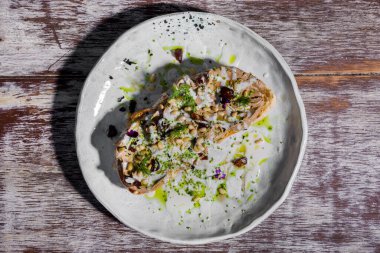 Et, buğday, çiçek yaprakları, dereotlu sandviç ve ahşap bir masada sos.