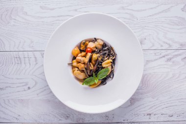 Kalamar, ahtapot, midye, domates ve soslu spagetti beyaz ahşap bir masada.