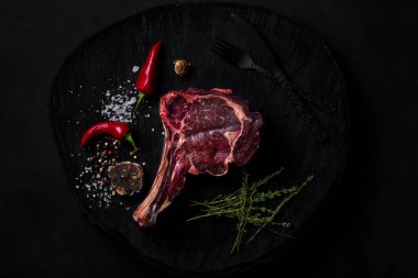 Kemiğe biberiye, tuz, sarımsak, kırmızı biber ve siyah bir tahta parçası üzerinde çatal ve çatalla biber. Yatay yönelim