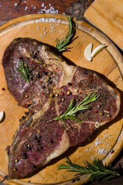 Kemiğin üzerinde ızgara et, ahşap bir tahta ve ahşap masa üzerinde sarımsak, biberiye, tuz ve biber. Dikey yönelim