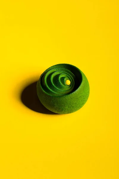 Green dessert with jam and chocolate on a yellow background