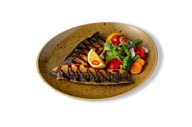 Fried fish fillet with tomatoes, asparagus beans, peppers, carrots, broccoli, parsley and mushrooms in a plate on a white background