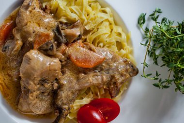 Kemiklerinde et, domates, mantar ve masada kekik olan makarna.