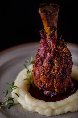 Grilled lamb on the bone with mustard, mashed potatoes, sauce, rosemary on a round plate. Vertical orientation 