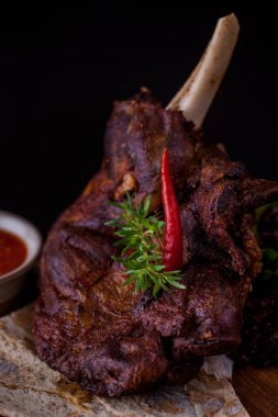 Grilled lamb on the bone, with red chili, red sauce, rosemary and pita bread on a wooden board. Vertical orientation 