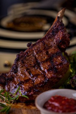 Grilled lamb on the bone, with red chili, red sauce, rosemary and pita bread on a wooden board. Vertical orientation 
