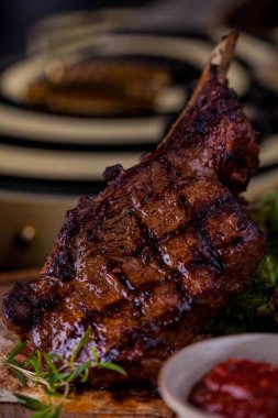Grilled lamb on the bone, with red chili, red sauce, rosemary and pita bread on a wooden board. Vertical orientation 