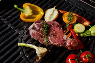 Grilled raw pork meat with rosemary, garlic, onion, pepper, zucchini, tomatoes lying on the smoldering coals. Horizontal orientation 
