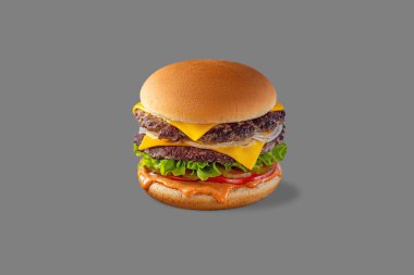 Double Cheeseburger with beef patty, fresh onion, lettuce, fresh tomatoes, pickles and paprika sauce. Burger stands on a gray background.