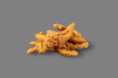 Chicken strips breaded with parmesan cheese. A portion of strips lies on a gray background.