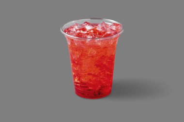 Lemonade with raspberry syrup and ice in a transparent plastic glass. The glass is on a gray background.