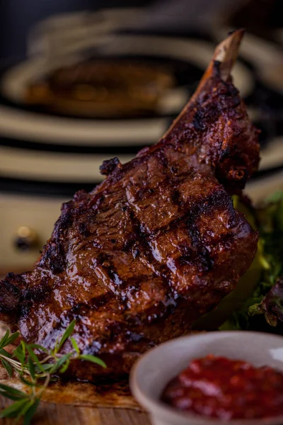 Grilled lamb on the bone, with red chili, red sauce, rosemary and pita bread on a wooden board. Vertical orientation 