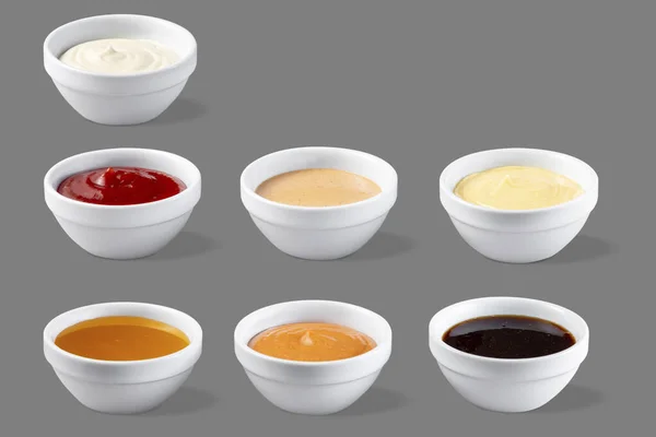On a gray background in white bowls are mango, chili, mayonnaise, cheese, ketchup, jack daniels, barbecue sauces.