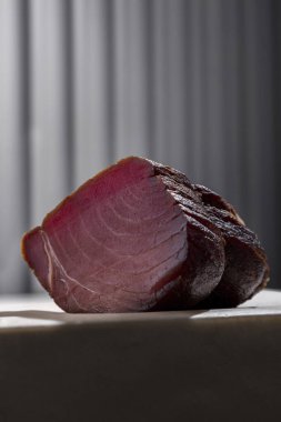 Smoked tuna fillet. Fillet of ocean tuna dried and smoked. A piece of fish lies on a beige packing paper on a white table. Behind you can see the gray corrugated hay.