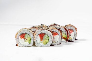 Sushi roll with eel and salmon. Filled with salmon, Philadelphia cream cheese, cucumber and avocado, wrapped in nori seaweed and rice. Each piece is wrapped in smoked eel fillet on top, drizzled with unagi sauce and sprinkled with black and white ses