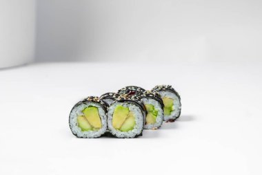 Maki sushi with avocado. Filled with avocado cubes wrapped in rice and nori seaweed. Sushi stands on a white background.