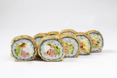 Hot sushi roll with trout. Filled with trout fillet, avocado, Japanese mayonnaise, cheddar cheese, wrapped in rice, nori seaweed and fried tempura. Sushi stands on a white background.