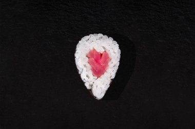 Rolls with nori, rice and tuna on a stone black background