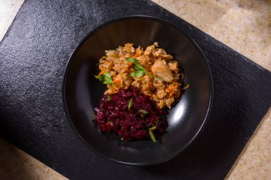 Rice plate with chicken, onions and beets on black and white stone background