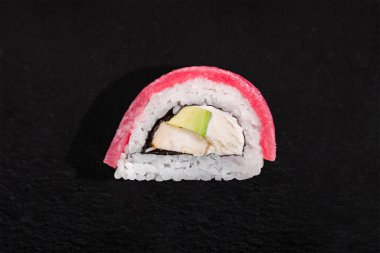 Rolls with tuna, rice, nori, eel and avocado on a black stone background