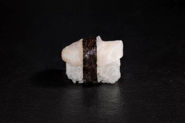 Roll nori, squid and rice on a black stone background