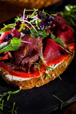 Çavdar ekmeği, ay çekirdeği, prosciutto ve domates soslu mikroyeşil ve Philadelphia küresi. Üzerine soğan mikro yeşil ve kişniş yaprakları serpiştirilmiş,.