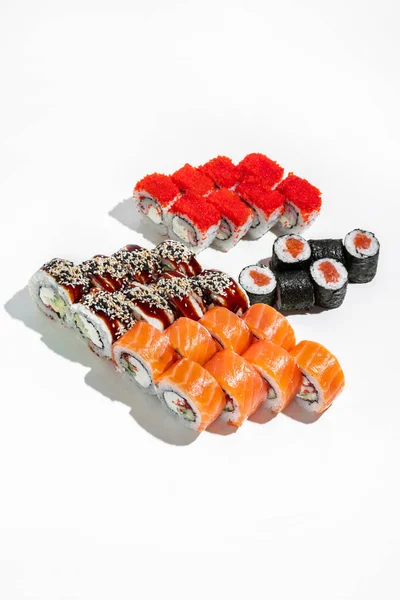 Red sushi set. Four sushi rolls stand on a white background. Philadelphia sushi with trout sashimi, maxi sushi with salmon, sushi with tuna and ugem and sushi with shrimp and flying fish caviar tobiko.